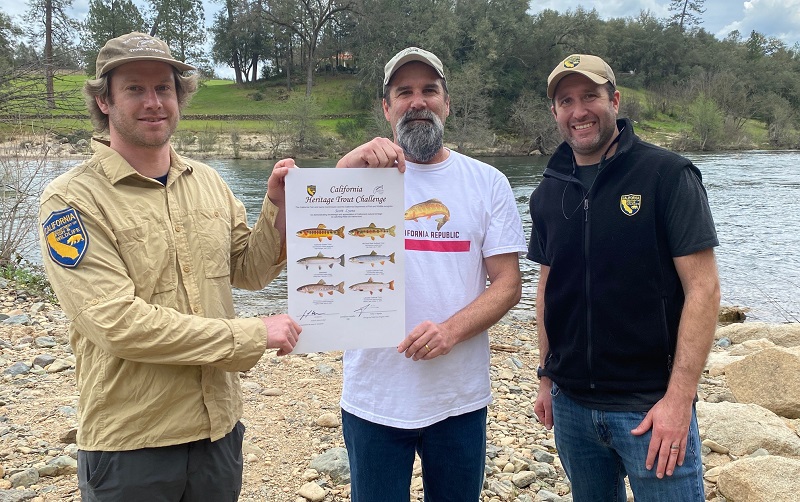 CDFW employee presents certificate to  angler next to river