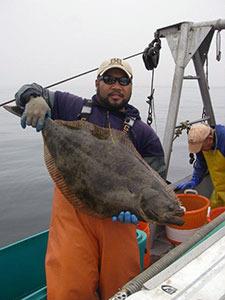 Environmental Scientist Travis Tanaka with a California halibut captured during a research cruise. CDFW file photo.