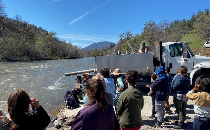 Schoolchildren watch as fall-run Chinook salmon fry are released into the Klamath River from a CDFW tanker truck.