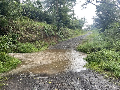 a stream with muddy water with a gravel road running through it