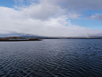 large lake with cloud and rainbow in distance