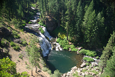 river with waterfall in forested mountains