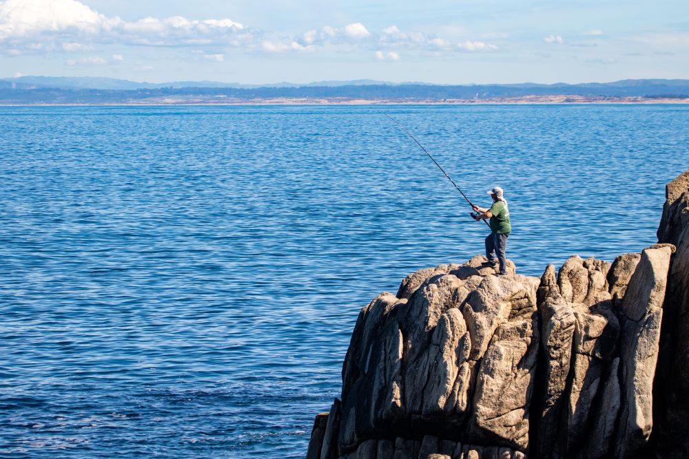 Man fishing from rock over ocean