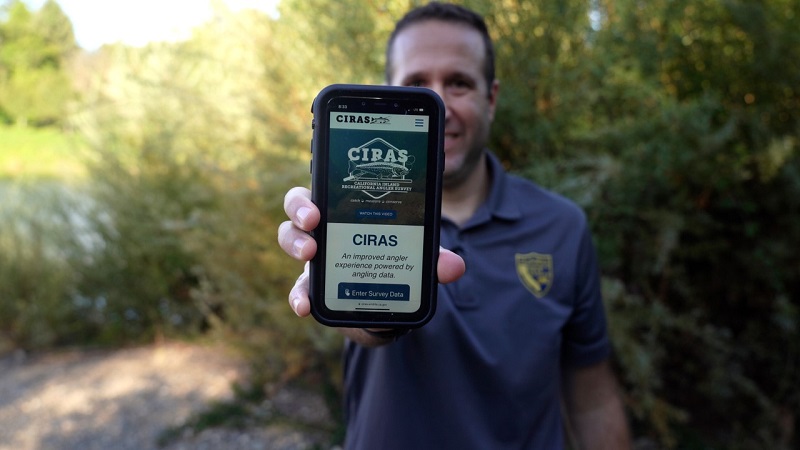 CDFW staffer holds up a cell phone to show the CIRAS online angler survey platform.