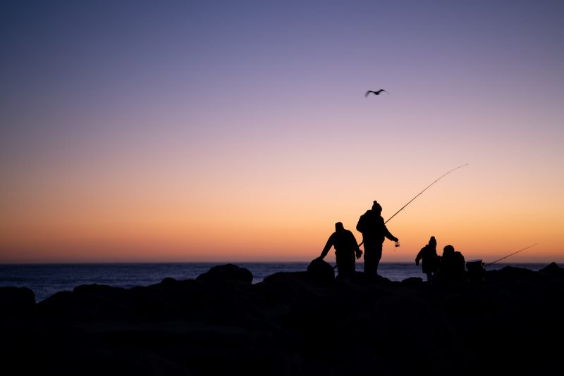 A group of anglers fish from a rock jetty.