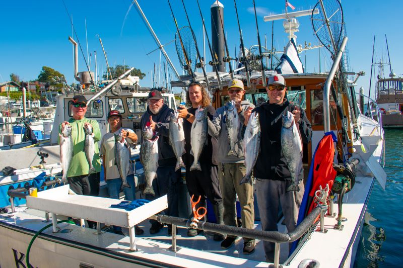 A group of anglers holding up their salmon catch.