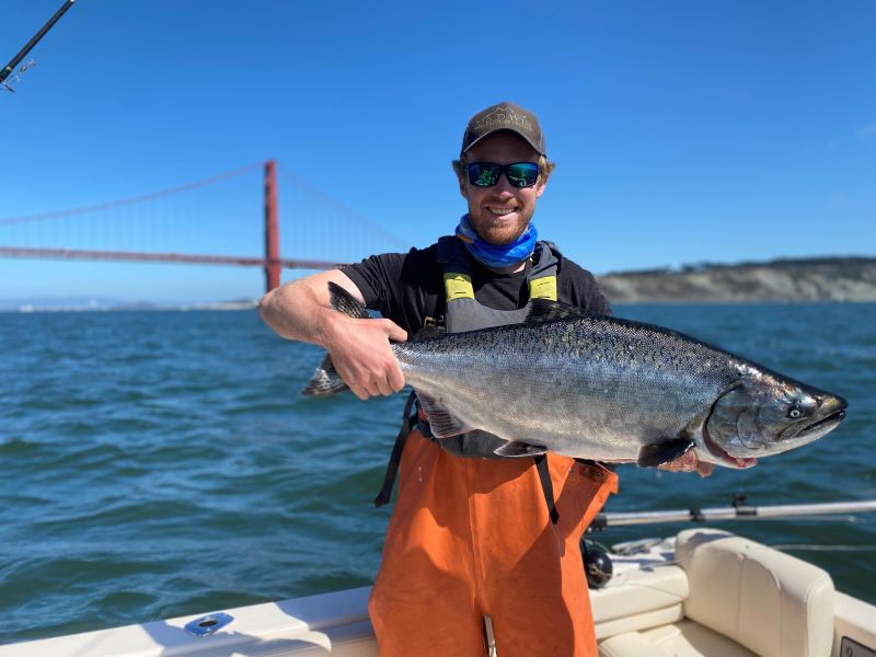 Man holding a salmon with the Golden Gate Bridge in background