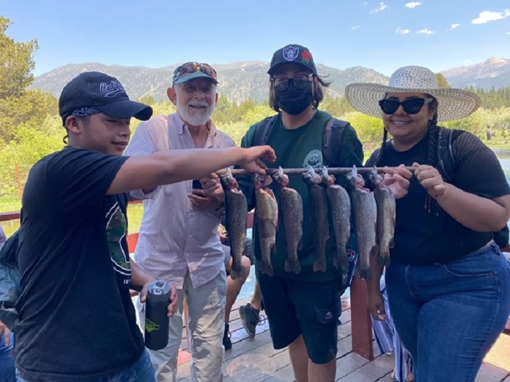 four happy anglers show off their catch of seven rainbow trout