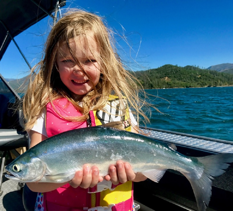Young girl with golden hair holding a large gray fish