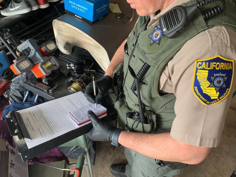 A CDFW wildlife officer takes notes on evidence collected during the investigation.