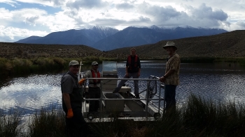 Biologists standing on an electroshocking boat on a lake