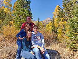 The Blair family of El Dorado County spends a fall day at the Hope Valley Wildlife Area in Alpine County - 4 people near rock with trees and blue sky in background