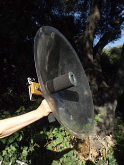 's arm holding a recording device to record songs of small gray birds