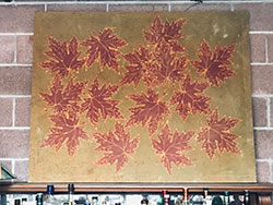 Scientist Jennifer Garrison is displaying a ceramic tile she decorated with purple leaves