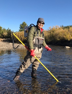 Kevin Kwak, with equipment in hand and on his back, prepares to electrofish a stream.