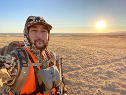 Scientist, Roy Kim, on a dry grassy area with the sun setting low in the horizon