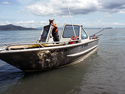 a man steers an aluminum boat in calm water
