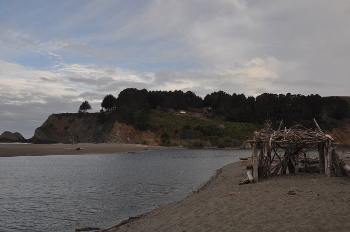 driftwood structure on sandy riverbank