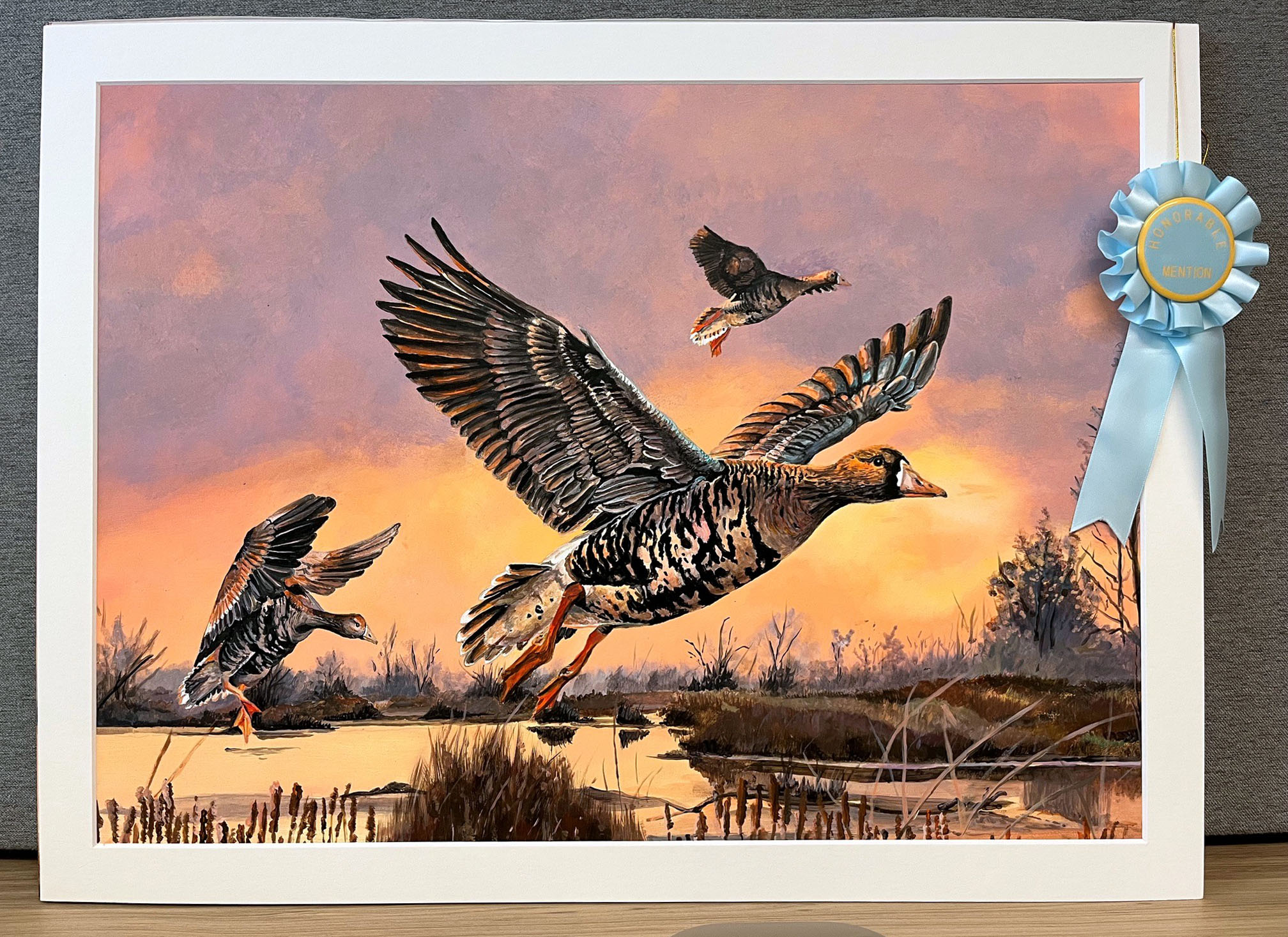 Photo of fourth place winning painting of the 2026 Duck Stamp Art Contest showing two greater white-fronted geese flying over a pond
