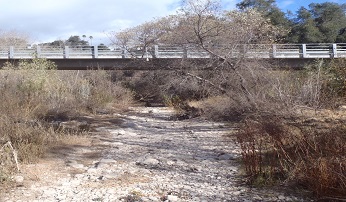 dry riverbed runs under a road