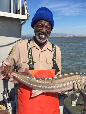 man on a boat holding a sturgeon