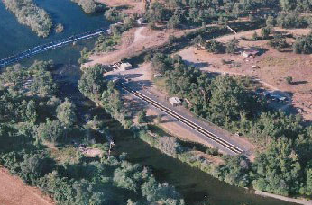 aerial view of raceway ponds along tree-lined river