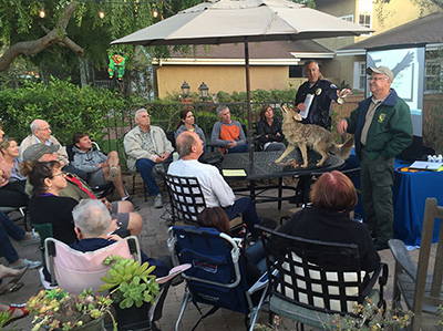 people gathered outside around a presenters and taxadermy coyote