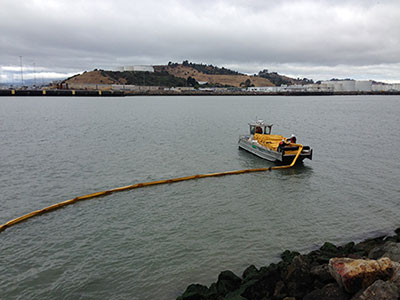a boat lets out a long yellow tube onto the water's surface